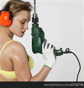 Young sexy woman holding a construction drill