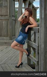 Young, sexy woman in short skirt stand on the old-time bridge.