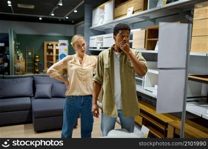 Young shocked married family couple buyer disappointed with expensive price in furniture store. Couple disappointed with price in furniture store
