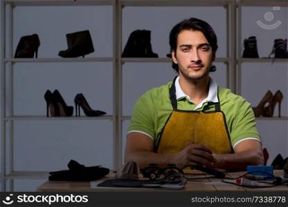 Young shoemaker in workshop at night  . Young shoemaker in workshop at night 