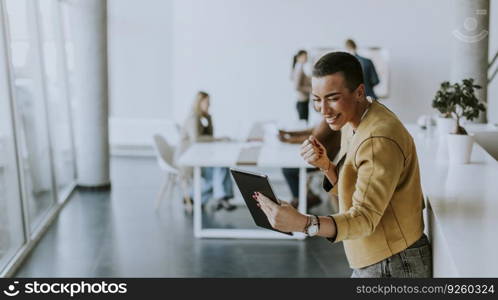 Young short hair business woman standing in the office and using digital tablet in front of her team