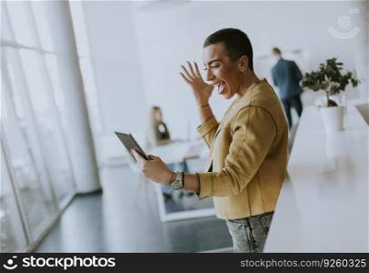Young short hair business woman standing in the office and using digital tablet in front of her team
