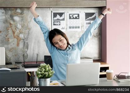 Young sian office woman stretching body for relaxing while working with laptop computer at her desk, office lifestyle, business situation