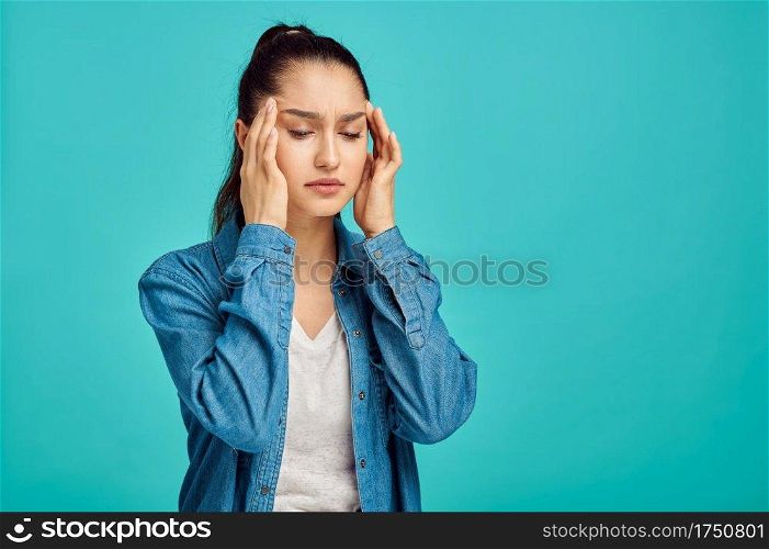 Young sick woman portrait, blue background, negative emotion. Face expression, female person looking on camera in studio, emotional concept, feelings. Young sick woman portrait, negative emotion