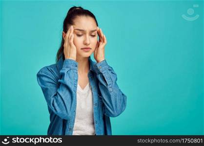 Young sick woman portrait, blue background, negative emotion. Face expression, female person looking on camera in studio, emotional concept, feelings. Young sick woman portrait, negative emotion