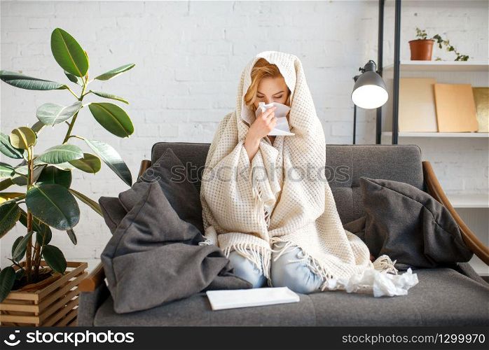 Young sick woman with kerchief sitting on couch under the blanket, illness. Female person with sickness face on sofa at home, catarrhal disease