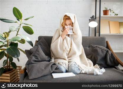 Young sick woman with kerchief sitting on couch under the blanket, illness. Female person with sickness face on sofa at home, catarrhal disease