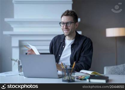 Young sitisfied male entrepreneur in glasses talking speaking during web conference via internet, using laptop at workplace in office, smiling german businessman team leader holding online meeting. Young sitisfied male entrepreneur in glasses talking speaking during web conference via internet