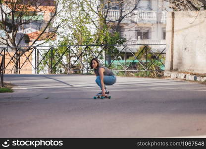 Young skater woman riding on her longboard in the village in casual wearing, freedom concept