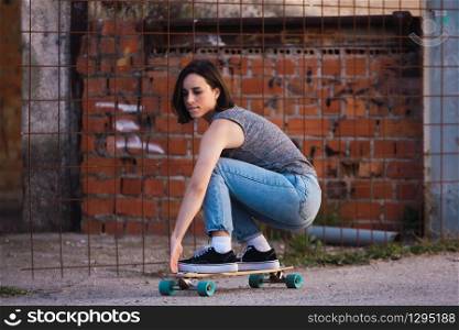 Young skater woman riding on her longboard in the village in casual wearing, freedom concept
