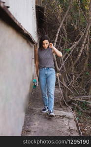 Young skater woman walking with her longboard in the village in casual wearing, freedom concept