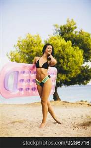 Young slim brunette woman sunbathe with an air mattress on the beach