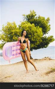 Young slim brunette woman sunbathe with an air mattress on the beach