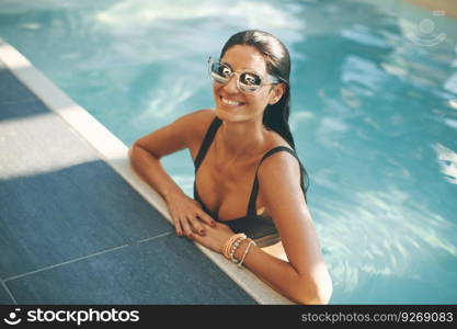 Young slim woman relaxing by swimming pool at hot summer day