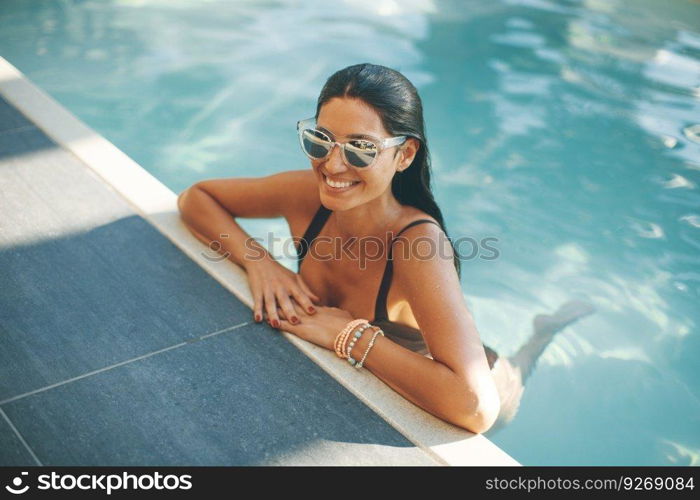 Young slim woman relaxing by swimming pool at hot summer day