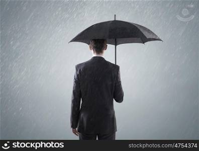 Young smart busienssman standing in the heavy rain
