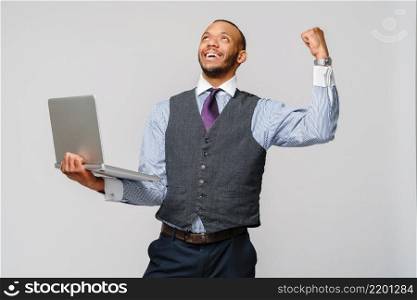Young smart shouting african-american businessman doing success win gesture and holding laptop pc.. Young smart shouting african-american businessman doing success win gesture and holding laptop pc
