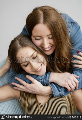 young smiley girlfriends hugging