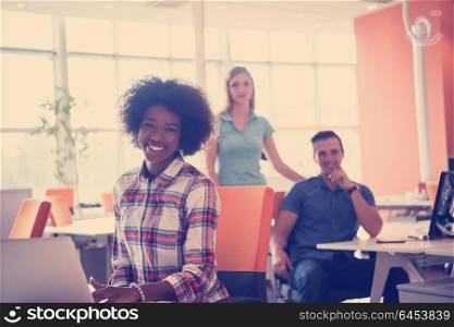 young smiling African American informal businesswoman working in the office with colleagues in the background