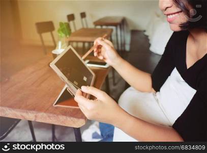 Young smiling asian woman holding credit card and using tablet making oline shopping