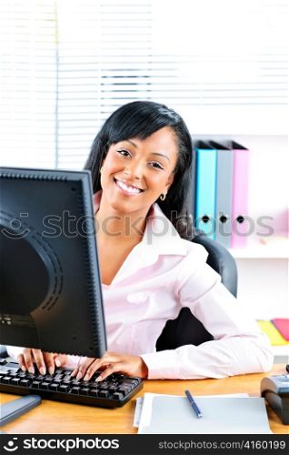 Young smiling black business woman at desk typing on computer