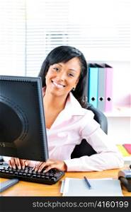 Young smiling black business woman at desk typing on computer