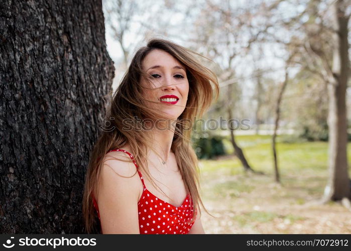 Young smiling blond woman with red dress moving her hair