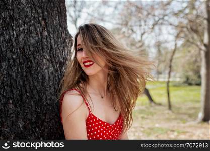Young smiling blond woman with red dress moving her hair