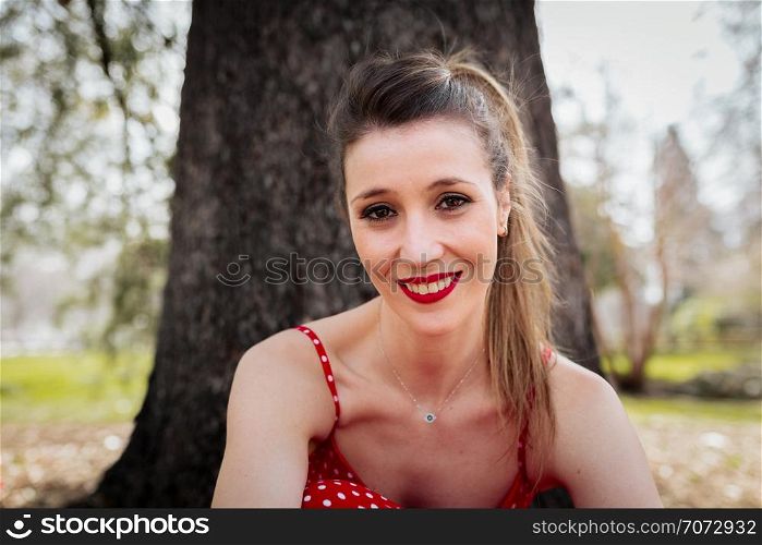 Young smiling blond woman with red long dress an a pigtail