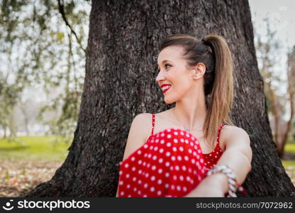 Young smiling blond woman with red long dress an a pigtail