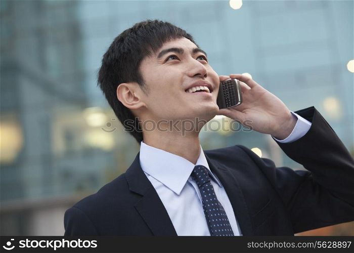 Young smiling businessman on the phone looking up