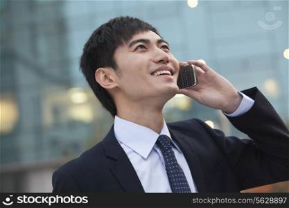 Young smiling businessman on the phone looking up
