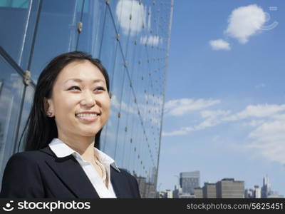 Young smiling businesswoman outside in front of glass building