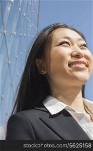 Young smiling businesswoman outside in front of glass building, close-up