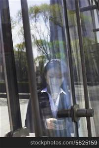 Young smiling businesswoman using the phone on the other side of a glass door