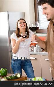 Young smiling couple drink red wine in modern kitchen