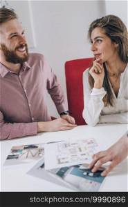 Young smiling couple in real estate agency office . Young Smiling Couple in Real Estate Agency 