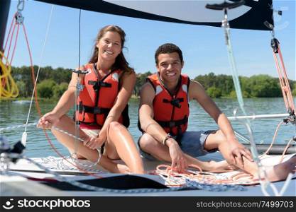 young smiling couple on a sailing boat at summer sunset