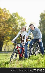 Young smiling couple on bicycles in the park