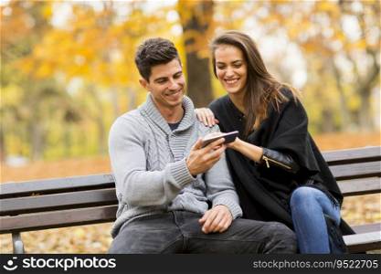 Young smiling couple sitting on bench in autumn park