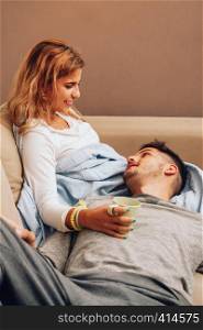 Young smiling couple together on sofa looking at each other with a cup