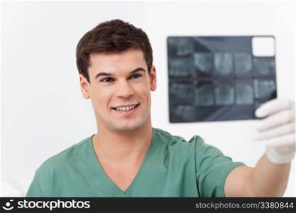 Young smiling doctor analyzing a dental X-Ray detail