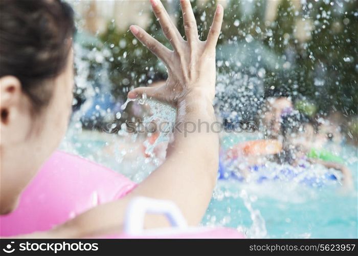 Young smiling family splashing and playing in the pool