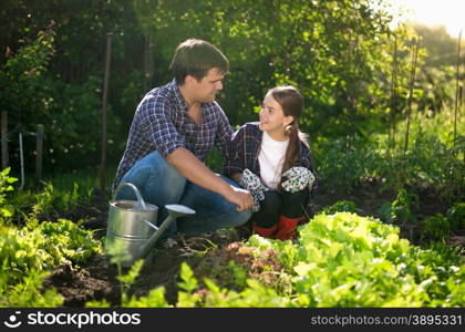 Young smiling father teaching daughter horticulture at garden