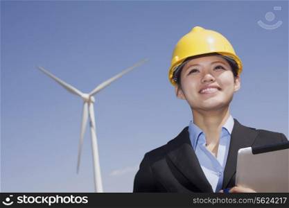 Young smiling female engineer checking wind turbines on site