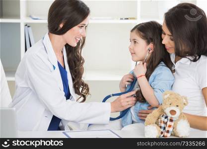 Young smiling female pediatrician doctor and her little patient with teddy bear. Pediatrician and her patient