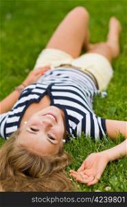 Young smiling girl lying on the grass with very narrow depth of field and focus on the eyes