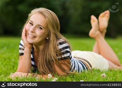 Young smiling girl lying on the park with very narrow depth of field and focus on the eyes
