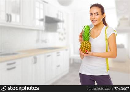 Young smiling girl with pineapple at kitchen