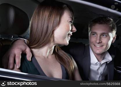 Young smiling, happy, couple sitting in their car and arriving at a red carpet event at night in Beijing